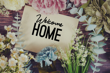 Welcome Home text with flowers bouquet decoration on wooden background