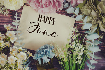 Happy June text with flowers bouquet decoration on wooden background