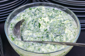 Bowl of green salad with a spoon in it. The bowl is filled with a creamy green sauce and the spoon is in the middle of the bowl.