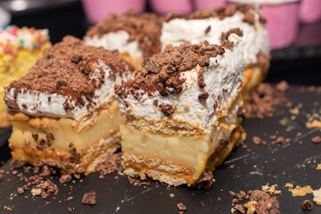 Dessert with chocolate chips and whipped cream on top. The dessert is cut into four pieces. The dessert is on a black surface.
