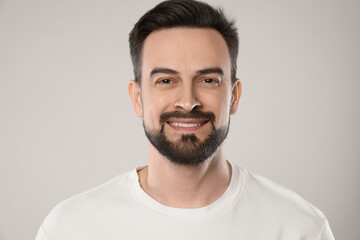Portrait of smiling man on grey background, closeup