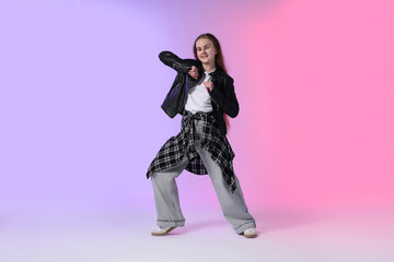 Girl in stylish clothes dancing on color background