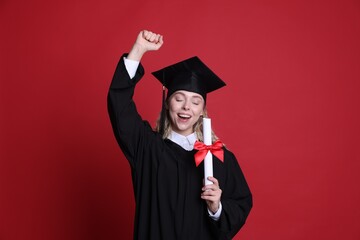Happy student with diploma after graduation on red background