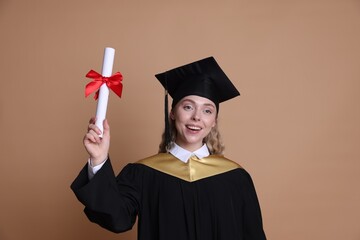 Happy student with diploma after graduation on beige background