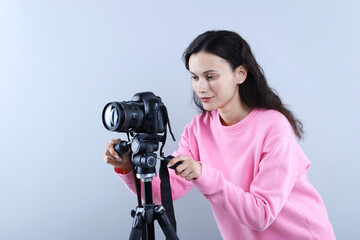 Woman with professional video camera on light grey background
