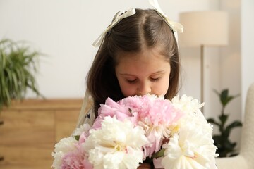 Naklejka premium Cute little girl with bouquet of beautiful peonies at home