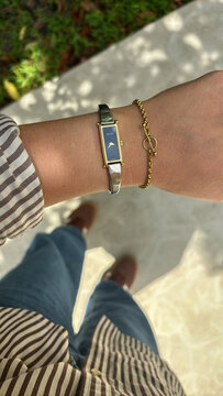 Stylish Gucci women&rsquo;s wristwatch paired with a gold bracelet, shown on a casual outfit.