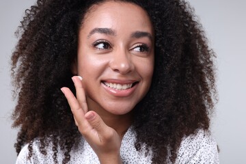 Beautiful Brazilian woman with collagen cream on gray background, closeup