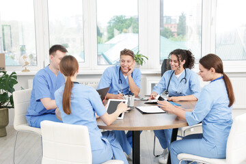 Fototapeta premium Medical students in uniforms studying together at table indoors