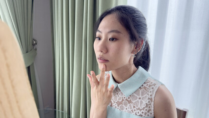 Asian woman standing in front of a mirror in a softly lit room with pastel curtains. Calm and serene atmosphere, concept of mindfulness, self-reflection, and personal well-being.