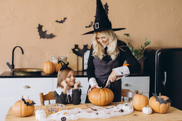 Mother and daughter carving pumpkins wearing witch costumes for Halloween party