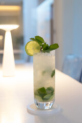 Mojito with soft light in cozy moment, fresh lime juice is added to sugar (or to simple syrup) and mint leaves. The mixture is then gently mashed with a muddler.