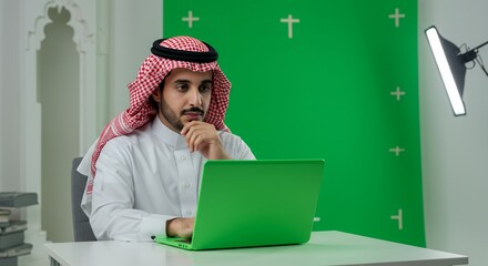 Thoughtful Saudi Man Works on Green Laptop in Modern Office