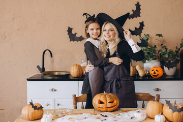 Mother and daughter wearing witch costumes carving pumpkins for Halloween