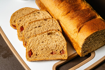 horizontal close-up photo of traditional artisan whole wheat sliced bread with guava jam next to a...