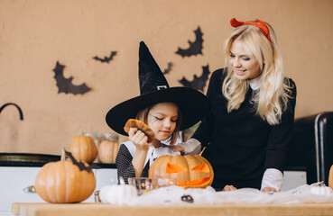 Mother and daughter carving pumpkins for Halloween party celebration