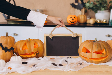 Woman holding empty blackboard with Halloween pumpkins and spiderwebs decorations