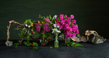 A floral arrangement with pale pink spirea, cinquefoil, and fragrant honeysuckle accented with driftwood. A romantic, organic arrangement.