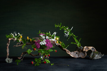 A floral arrangement with pale pink spirea, cinquefoil, and fragrant honeysuckle accented with...