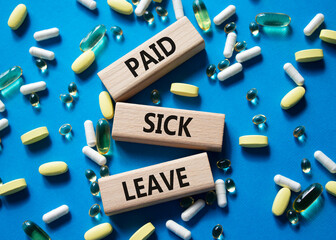 Paid Sick Leave symbol. Concept words Paid Sick Leave on wooden blocks. Beautiful blue background...