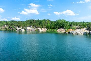 Fototapeta premium The abandoned Korostyshiv quarry, with its deep blue waters and rugged cliffs, has become a scenic spot for recreation, fishing, and swimming.