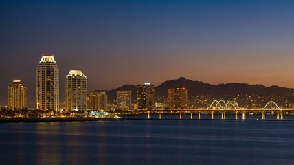 Obraz premium Night View of Illuminated Skyscrapers and Bridge in a Vibrant City Skyline During Twilight