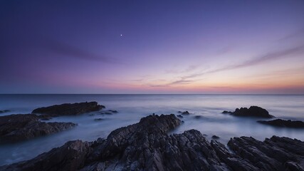 Fototapeta premium Sunset Over Rocky Coastline Captures Tranquil Waves and Colorful Sky During Early Evening at Seaside