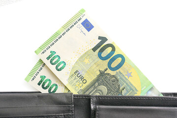 Hundred euro banknotes in black leather wallet. Close up of money sticking out. Isolated on white background. Financial savings concept. Personal income or cash payment. European currency macro view.