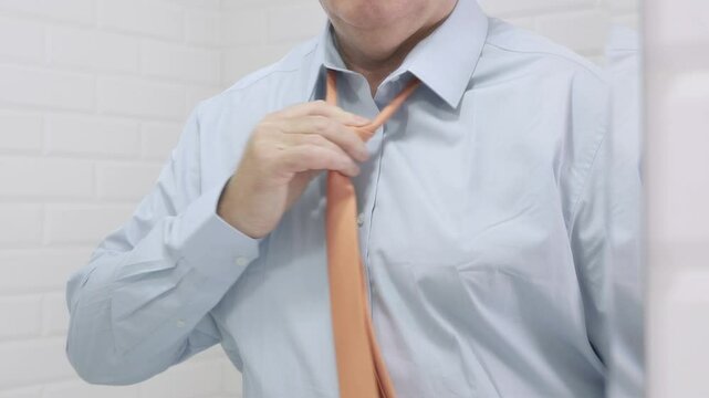 Blurred Shooting with a Borred Businessman in the Mirror Wearing a Blue Shirt and Untying a Tie from His Neck.