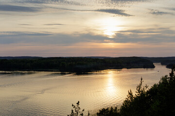 A peaceful sunset over the Skerries of Lake Ladoga, with calm waters and dense forests on the...