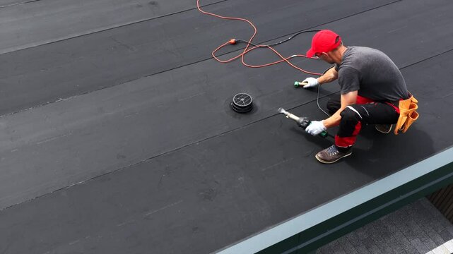 Worker Installs EPDM Roofing Material on a Flat Roof in Residential Area During Daylight Hours