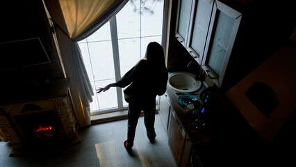 Young woman enjoying her favorite music, dancing in the kitchen in the morning.