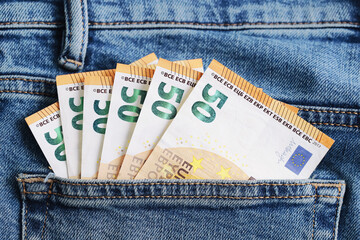Fifty euro banknotes sticking out from jeans pocket. Close up of money in blue denim fabric....