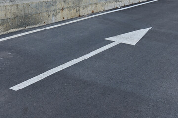 Directional arrow on asphalt road surface in urban area