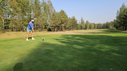 Obraz premium Golfer prepares to take a shot on the course surrounded by trees