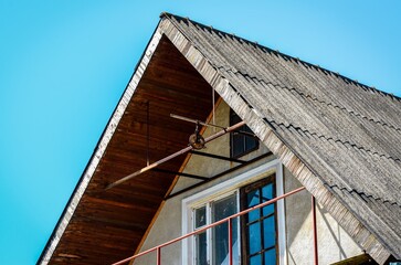A house with a slanted roof and a window. The roof is made of wood and the window is made of glass