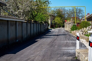 A street with a yellow metal pole in the middle. The pole is attached to a red sign