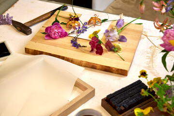 Botanical printmaking preparation – colorful fresh flowers arranged on board, DIY floral art...