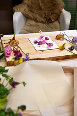 Botanical printmaking preparation – colorful fresh flowers arranged on board, DIY floral art setup in natural palette with hammer and craft tools, top view