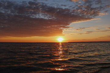 Dramatic cloudy sunset over the sea with a golden sun reflection on the water