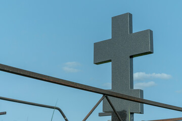 Marble cross in a serene cemetery. In the embrace of nature a granite cross stands as a testament...