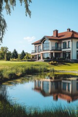 Fototapeta premium Beautiful modern house with large windows overlooking calm pond and lush green lawn on a sunny day in a serene landscape
