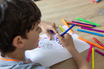Child draws fractal patterns with crayons as part of art therapy. Creative activity for emotional...