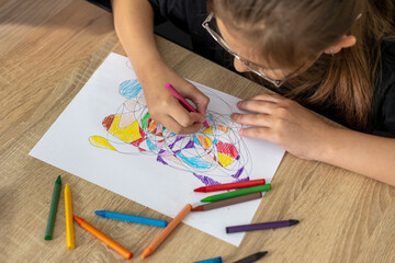 Child draws fractal patterns with crayons as part of art therapy. Creative activity for emotional...