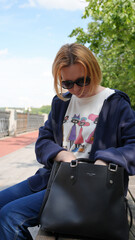 Young woman in sunglasses with mobile phone in the park on a sunny day