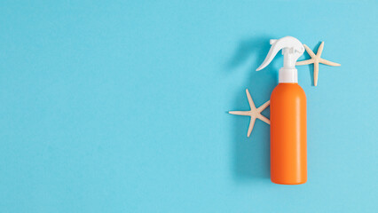 Orange bottle of tanning oil and starfish on a blue background. Sunscreen lotion, cream, sunscreen. Banner.