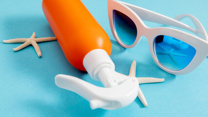 Close-up of sunscreen lotion, sunglasses, starfish. Summer vacation, UV protection concept. Orange bottle of sunscreen, sunscreen. Banner.