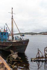 Rusty fishing boats and sunken shipwrecks in the famous ship graveyard of Teriberka under overcast...
