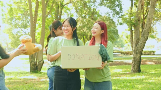 Group female volunteers together carry cardboard boxes in a park collect donations help victims natural disasters, wars and poor and homeless. They are happy volunteer with their cheerful appearance.