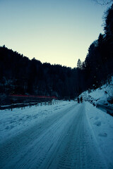 Snow-covered pathway through the Alps at dusk with two figures walking in the distance